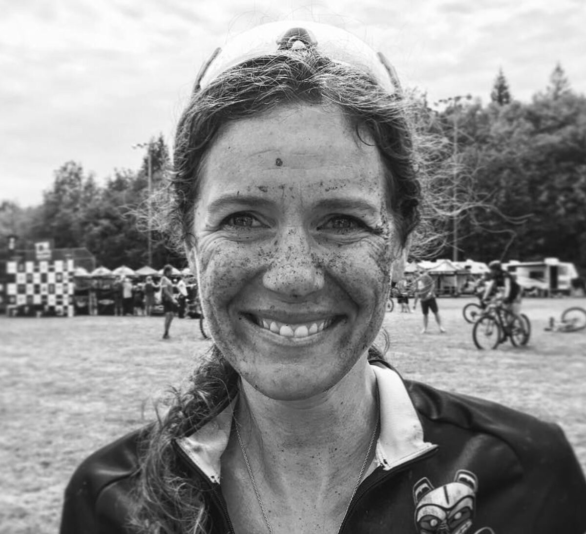 Kelli Emmett cycling race covered in mud smiling at camera